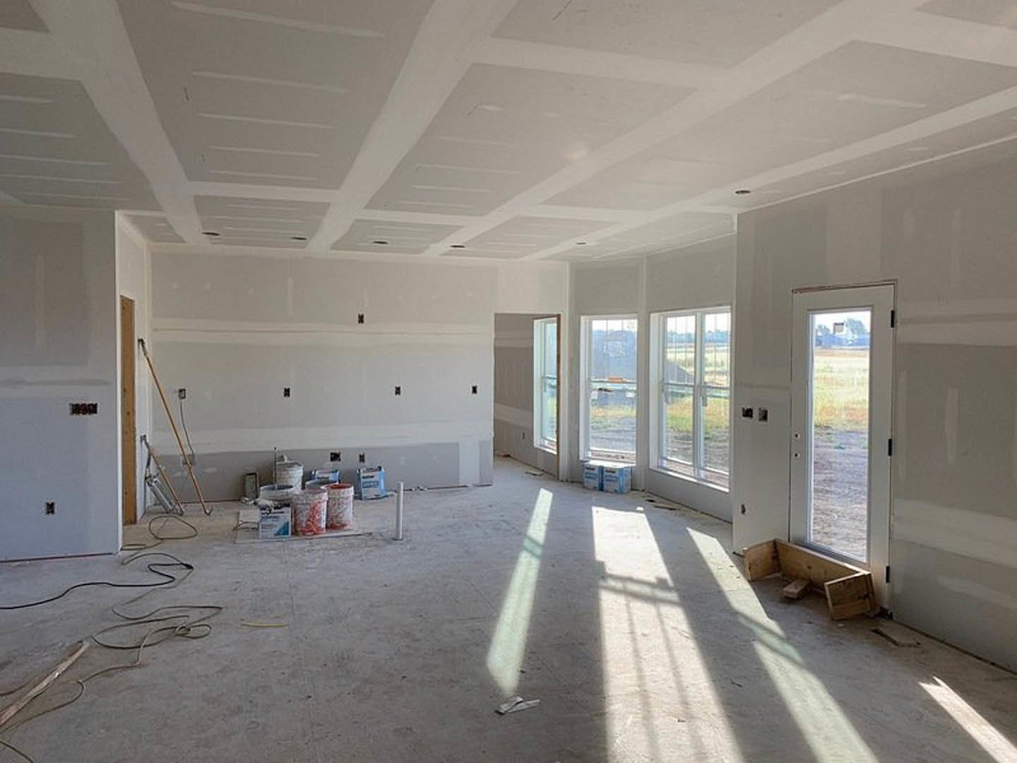 Sunlit room with smooth white plaster walls and ceiling, glass windowed door, wooden bench, and window letting in daylight.