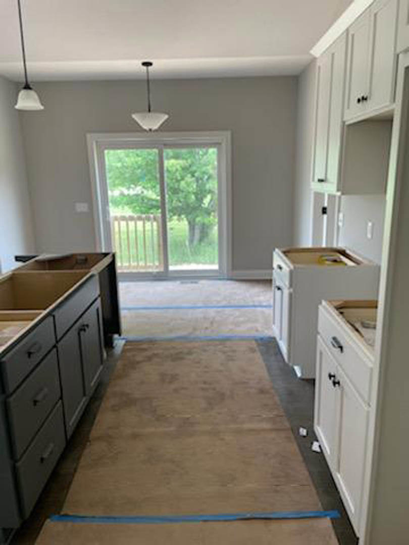 Modern kitchen featuring white cabinetry, stainless steel sink, stone countertop, a door leading outside, and a window allowing natural light