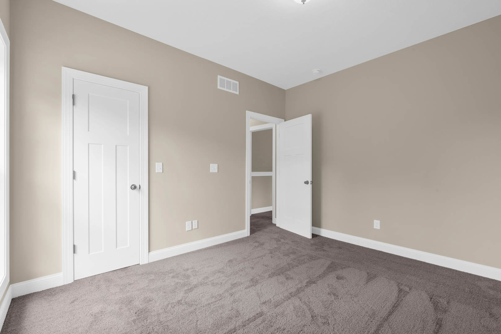 Open white door leading into carpeted room with white walls, white trim, and window with white frame