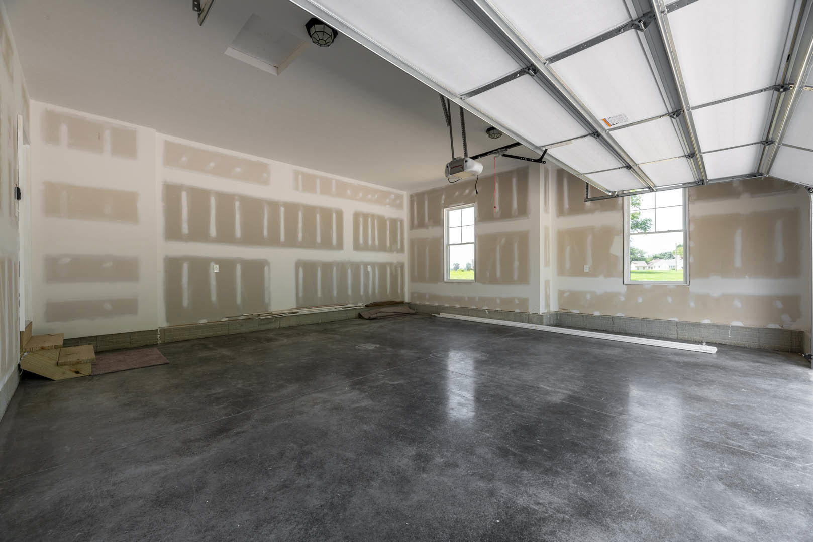 Concrete floor with white trim, large window framed in white overlooking trees, plaster walls, exposed ceiling beams