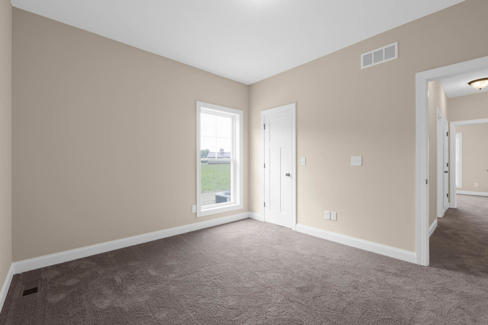 White paneled door with chrome handle, beige carpet flooring, wall vent, window showing neighboring house, white baseboards and molding
