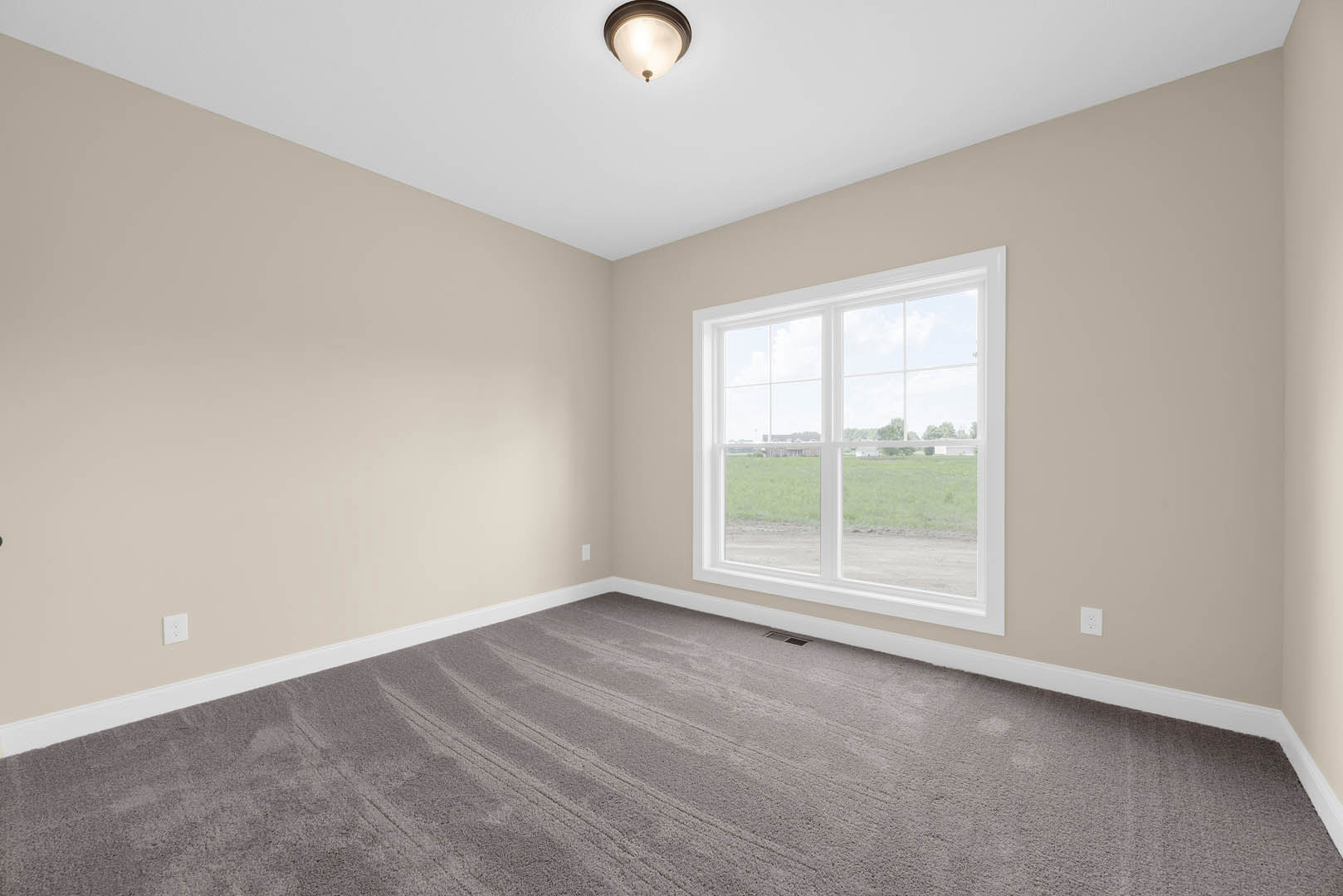Bedroom with grey carpet, white walls, ceiling light fixture, large window overlooking grassy field