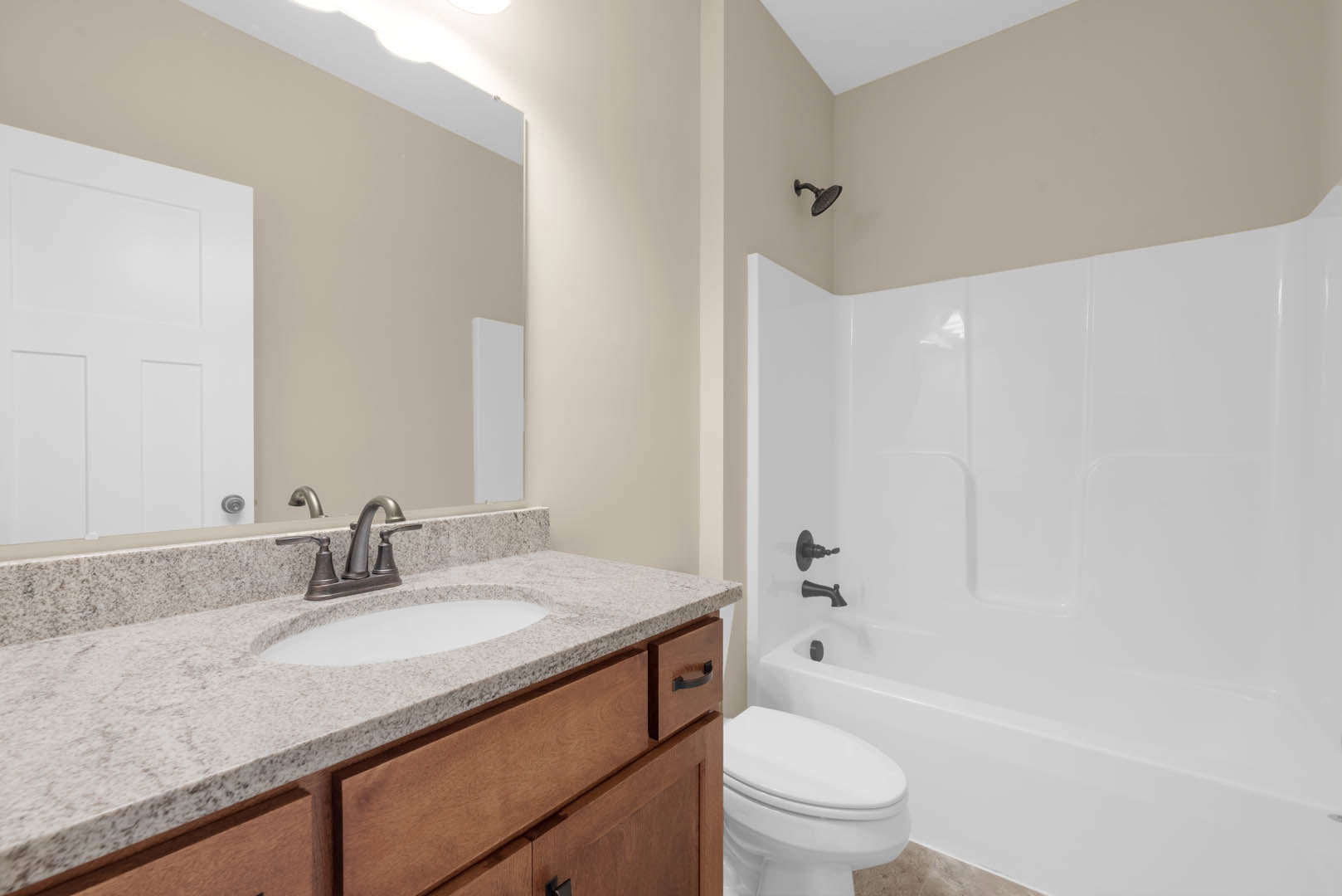 Modern bathroom featuring a white ceramic sink with chrome faucet, glass-enclosed shower with tiled walls, white toilet, and paneled door; light-colored countertop and cabinetry