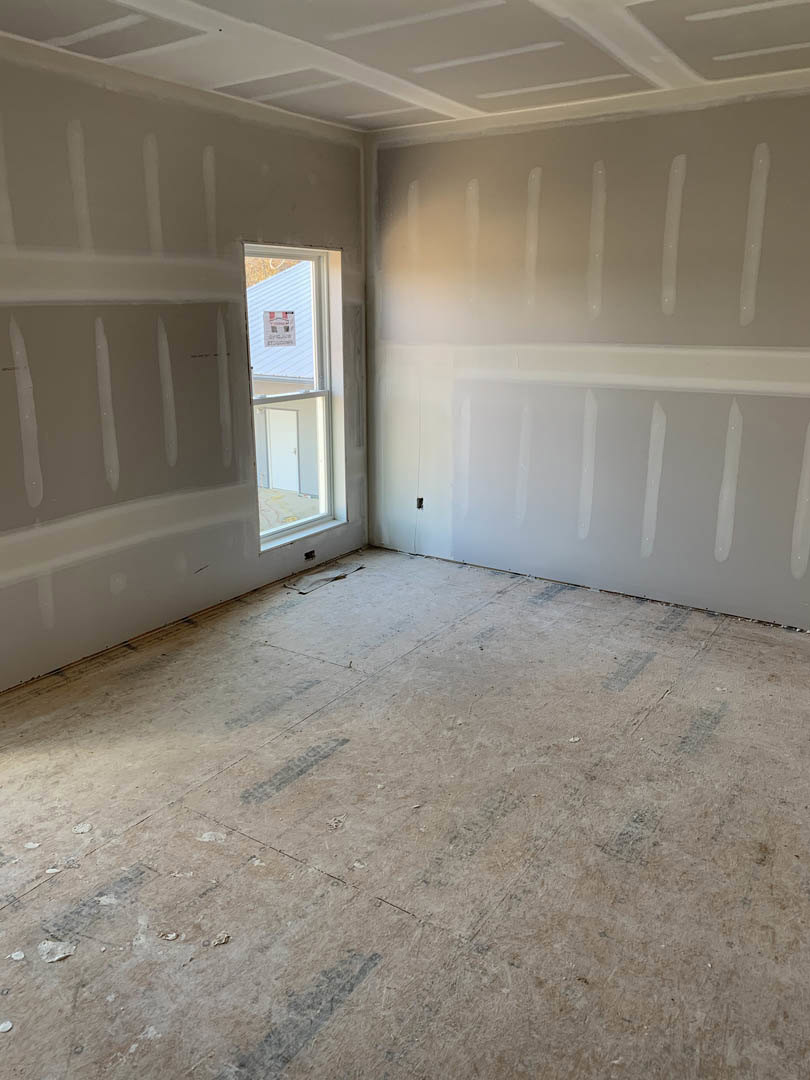 White-painted room featuring a large window, smooth plaster walls, light-colored flooring, and a white ceiling with recessed lighting.