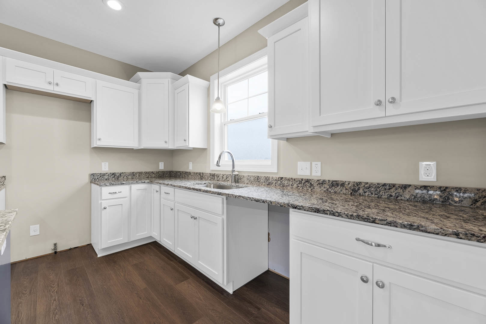 White kitchen with shaker cabinets, speckled granite countertops, stainless steel faucet, and built-in appliances.