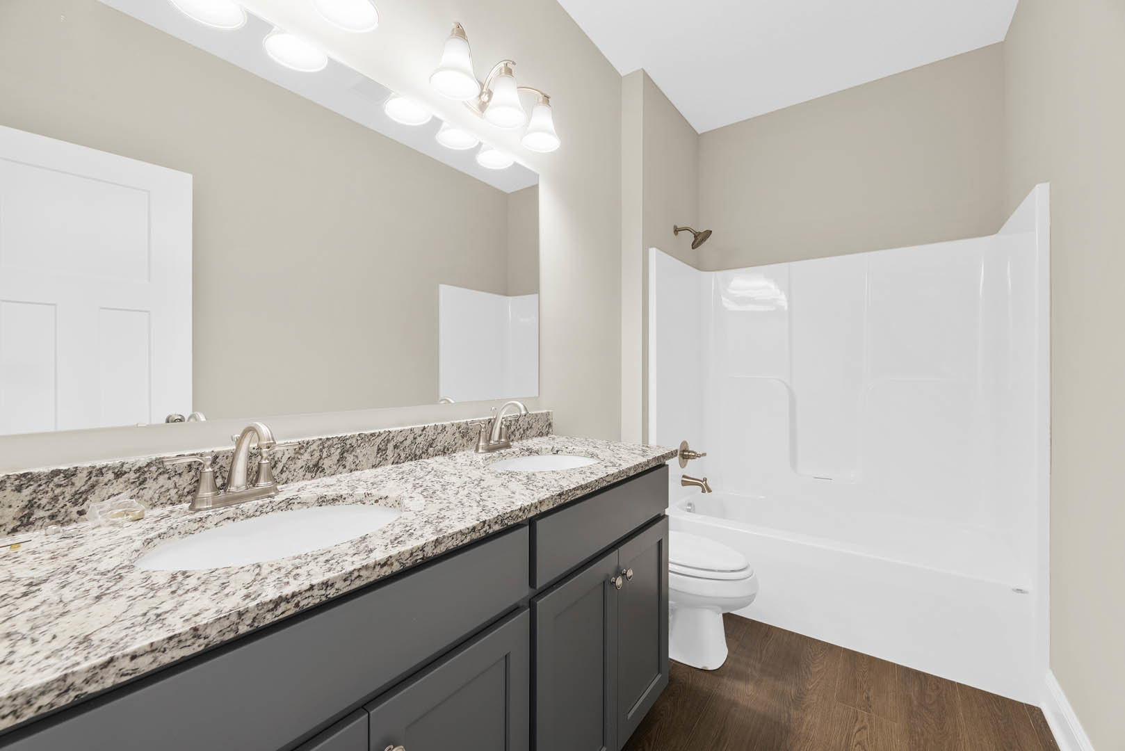 Bathroom featuring a marble countertop, undermount sink, white toilet, and a walk-in shower with white tile walls