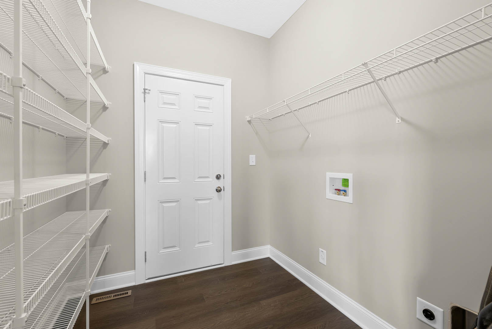 White paneled door with silver knob, built-in white shelves on wall, dark wood flooring, white walls and ceiling
