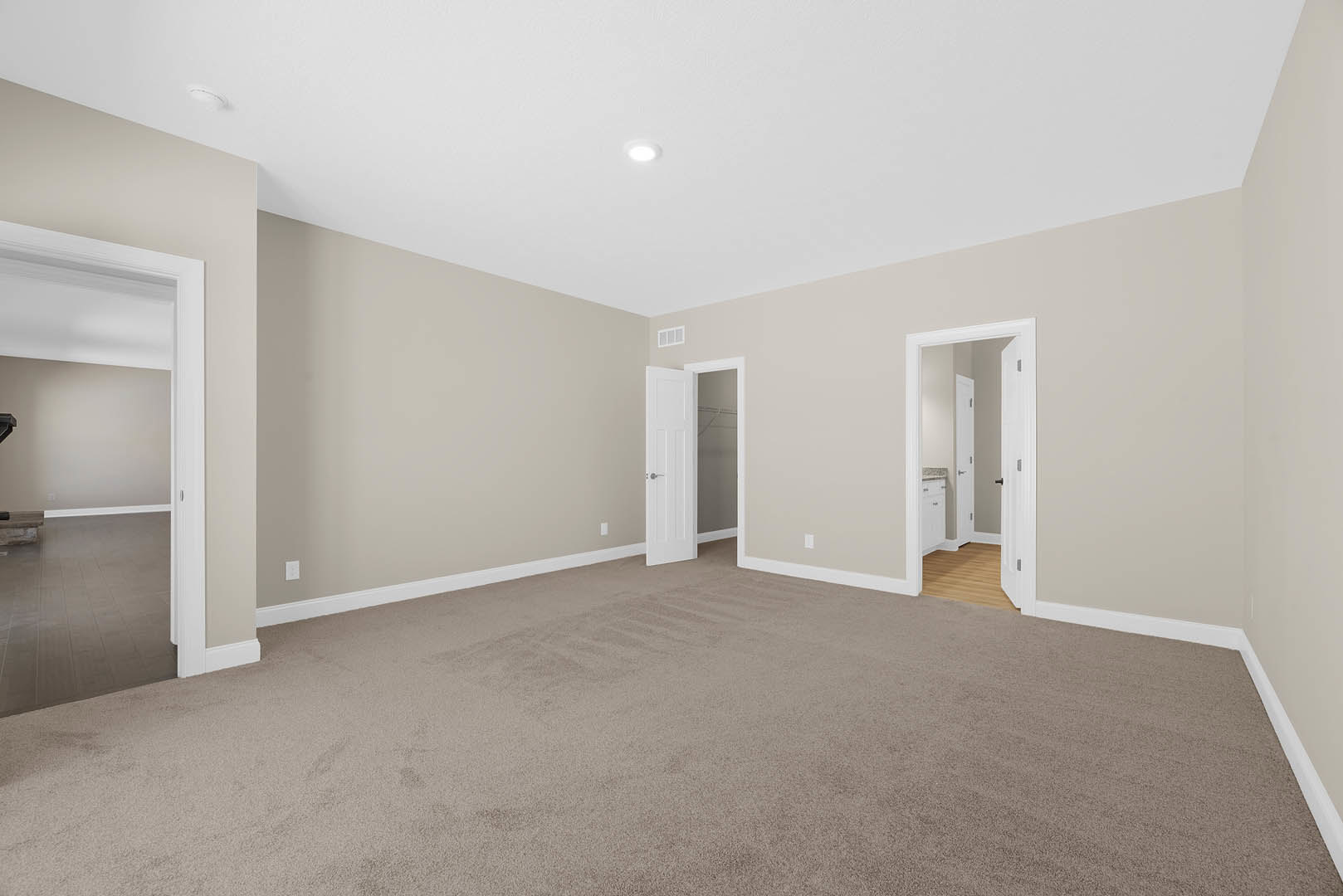 Beige carpeted floor, white walls, white door with matching frame, ceiling light fixture, simple molding along ceiling and baseboards