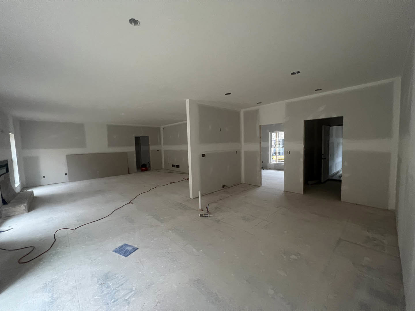 White plaster walls, red wire lying across light-colored floor, blue square accent on white surface, window with white frame, close-up of door.