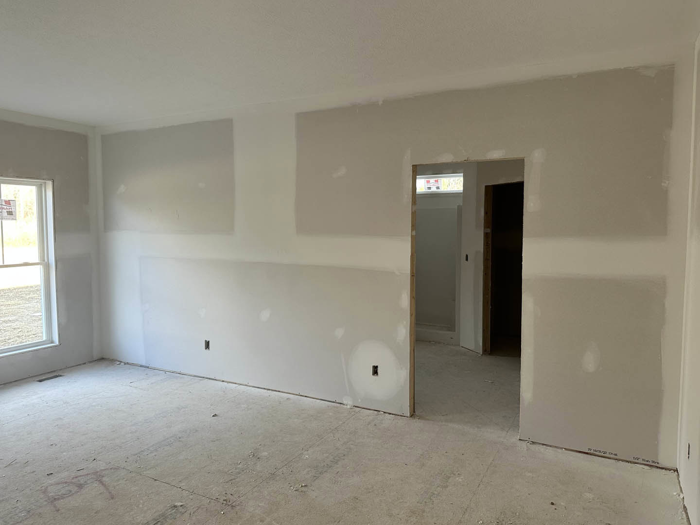 Open doorway leading into a room with light-colored plaster walls, wooden door frame, and visible window; neutral flooring and ceiling finishes create a clean, modern interior.