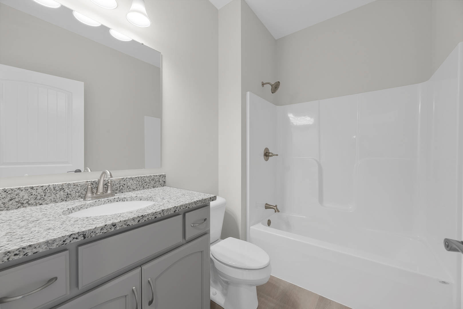 Modern bathroom featuring white ceramic sink with chrome faucet, white toilet, tiled walls, and white bathtub; white door and ceiling visible in background.
