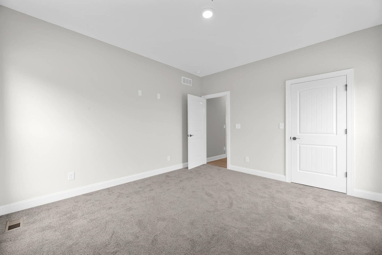 White-walled room with plush carpet, white door featuring black handle, recessed ceiling light