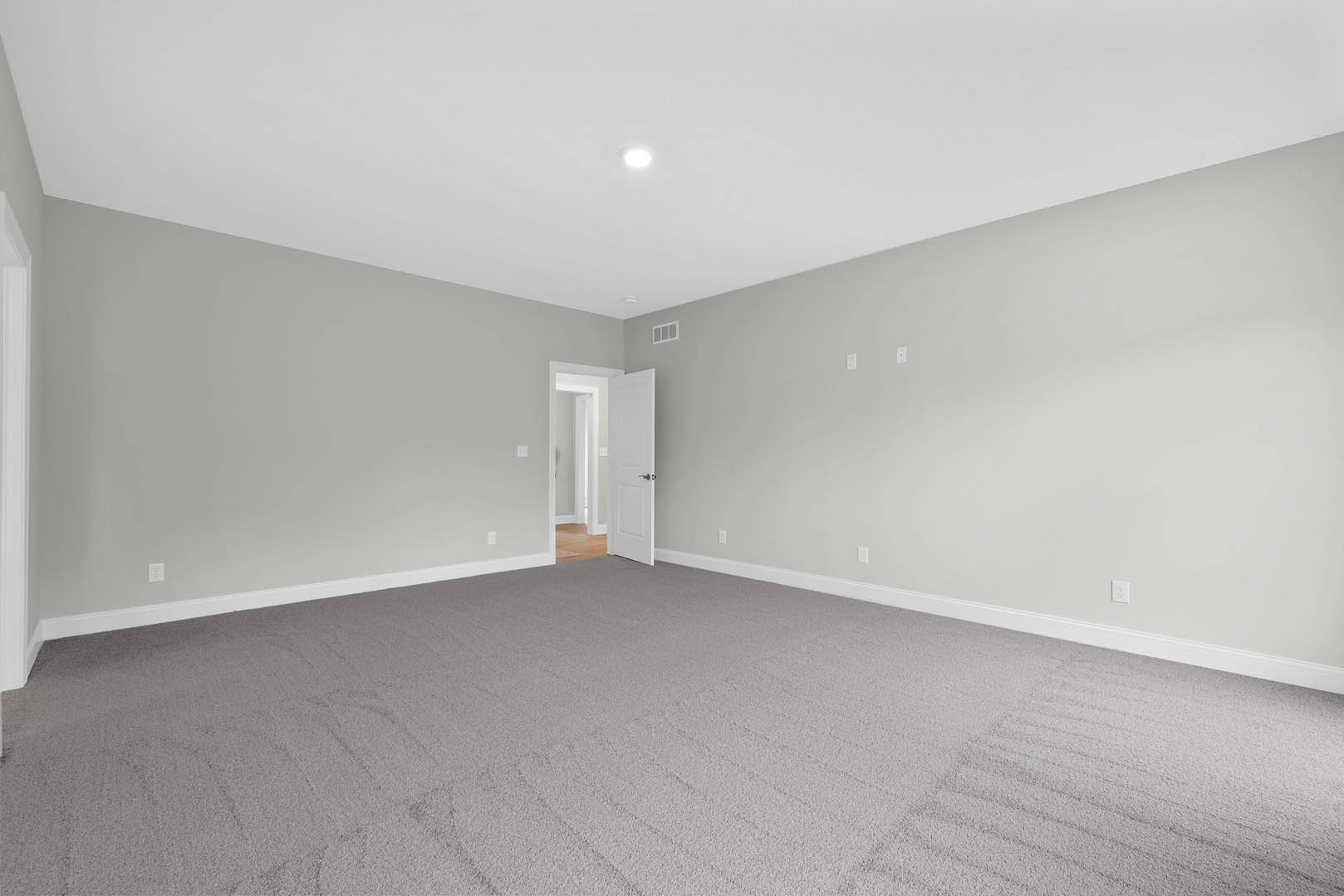 Carpeted room featuring a white door with black handle, white pillar with wall niche, and ceiling light fixture.