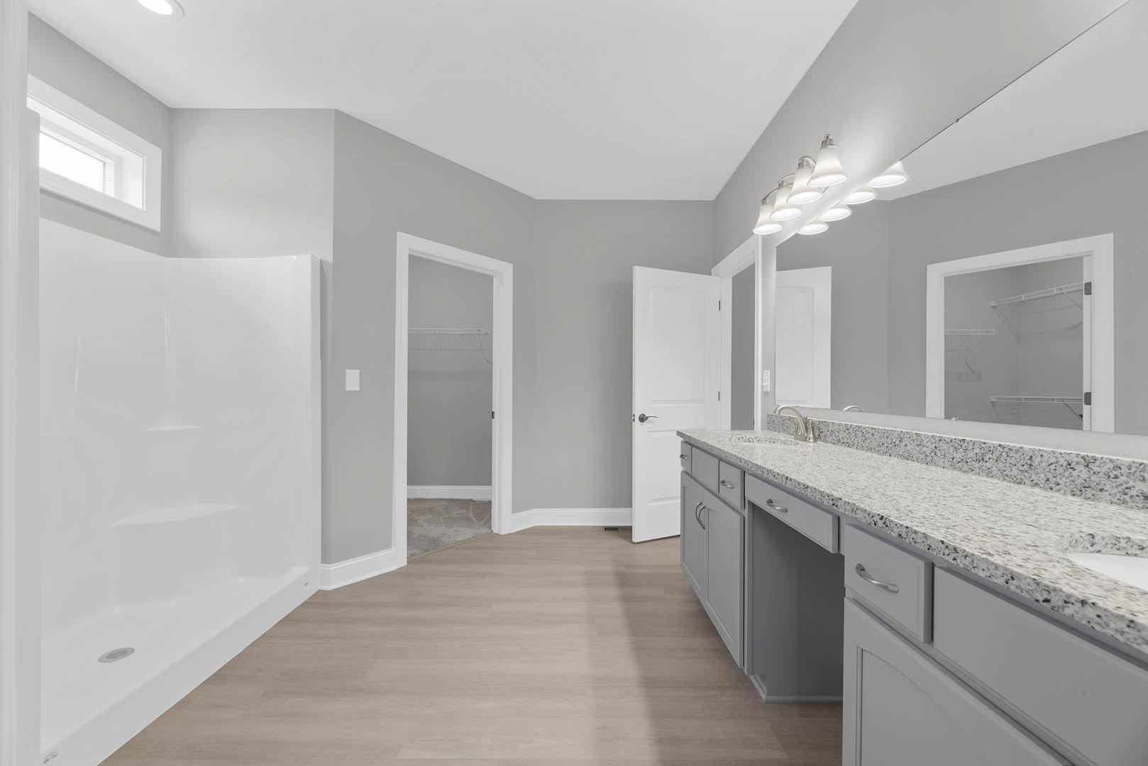 Bathroom featuring a marble countertop vanity, white shower enclosure, wood flooring with white trim, glass door closet, and white framed door.