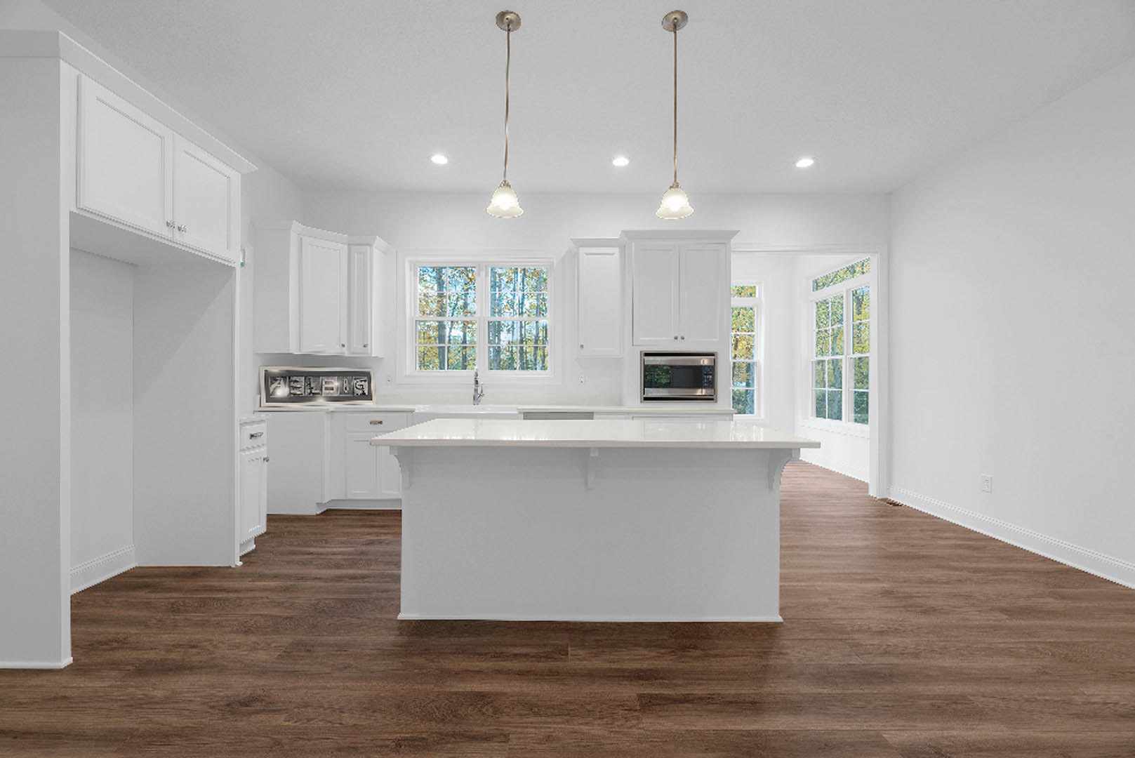 White kitchen island with quartz countertop, wood plank flooring, white cabinetry, stainless steel microwave, pendant lights, open shelving with framed photos, and a knife on the