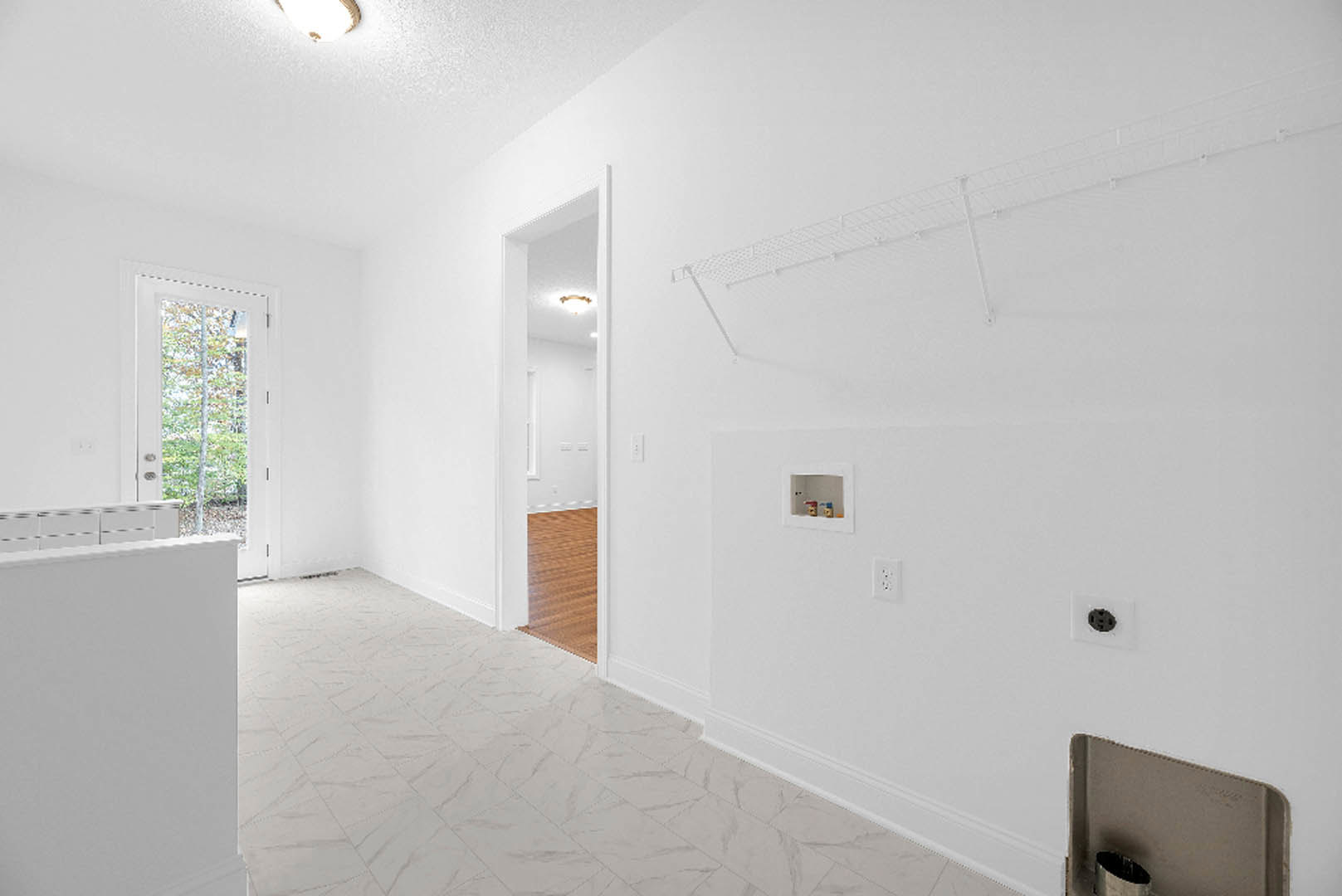 White-painted room with open door featuring a rectangular window, black handle, and visible wood flooring.