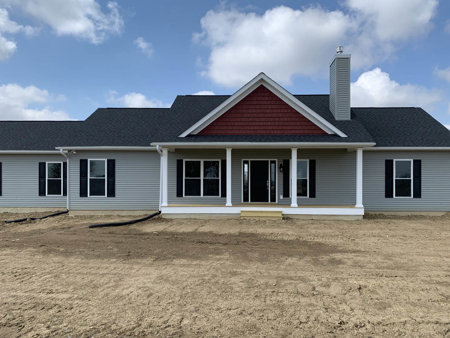 Two-story house with white siding, black door and window shutters, white trim, and a dirt yard in front