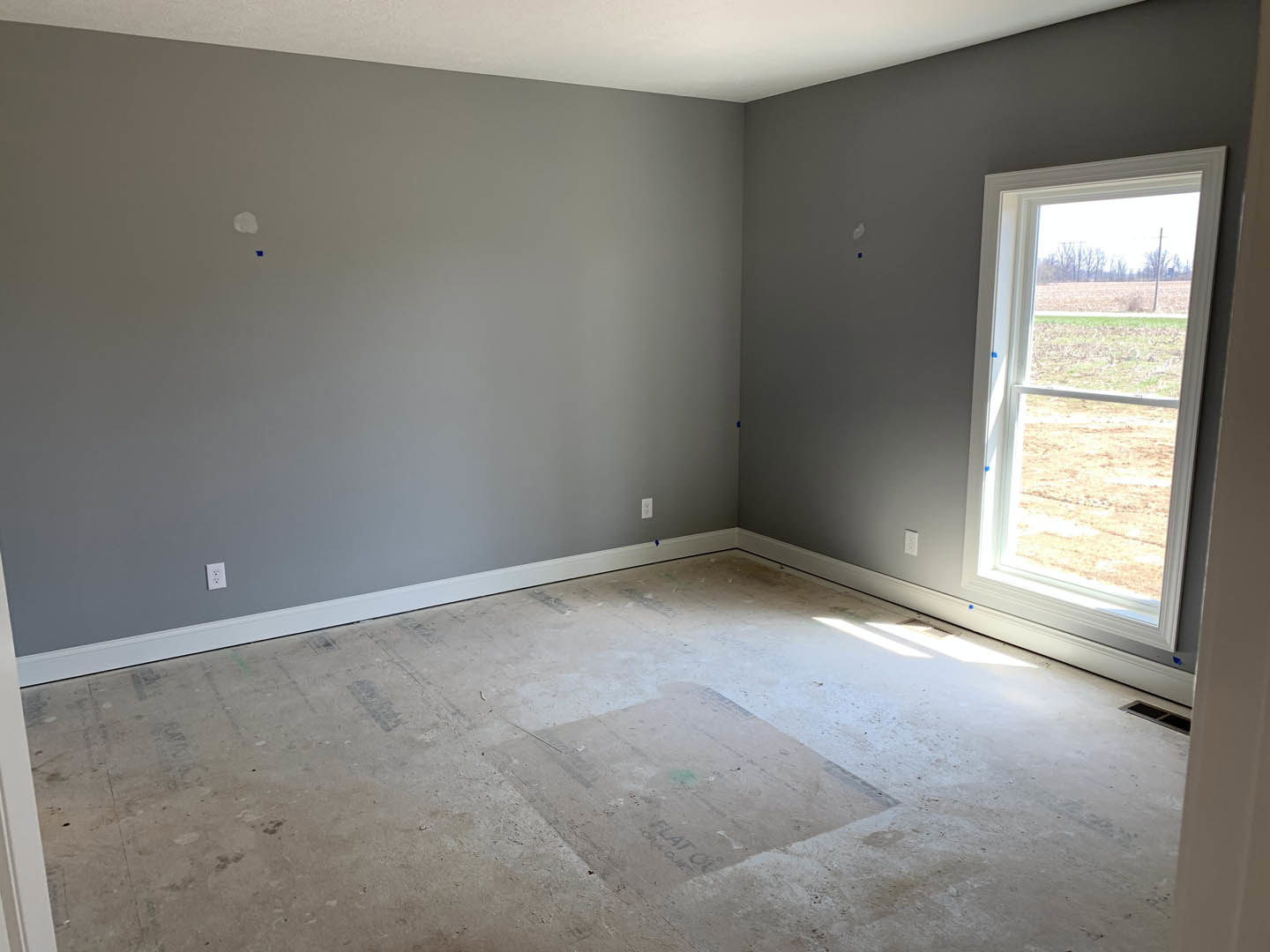 Bright room featuring two large windows, grey accent wall, white surrounding walls, and smooth tile flooring.