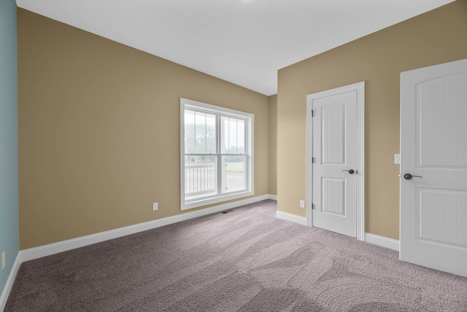 White paneled door with black handle, beige carpet flooring, white walls with base molding in a residential interior room