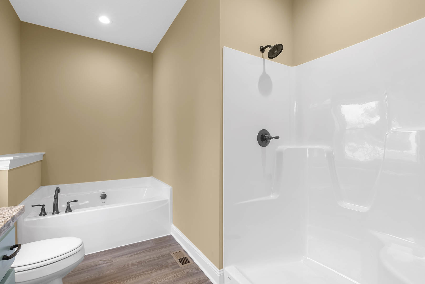 Modern bathroom featuring a glass-enclosed shower with round shower head, freestanding bathtub with chrome faucet, white toilet, and light gray tile walls