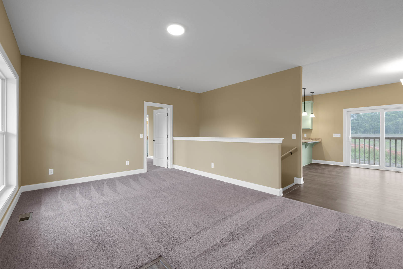 Carpeted room with white paneled door, sliding glass door opening to deck, ceiling light fixture, and white trim molding