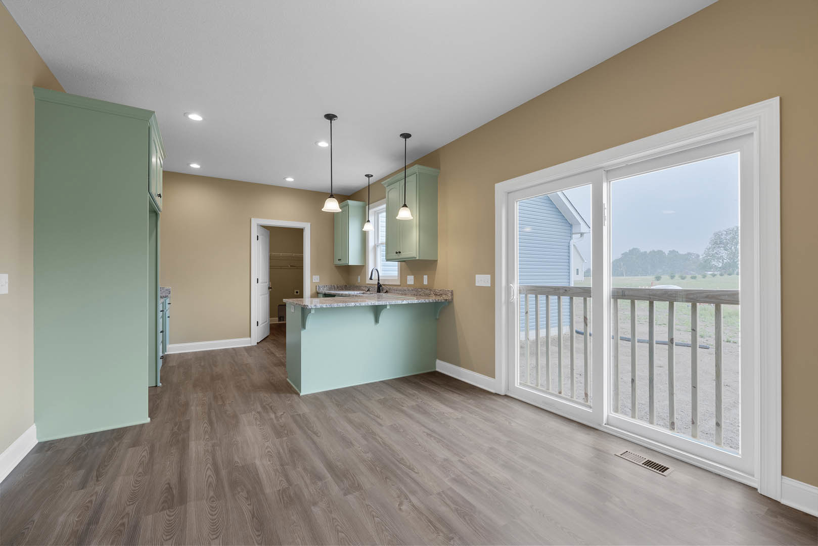 Open kitchen and dining area featuring marble countertop, sliding glass door overlooking a field and house, wood flooring, light blue walls, and floor vent
