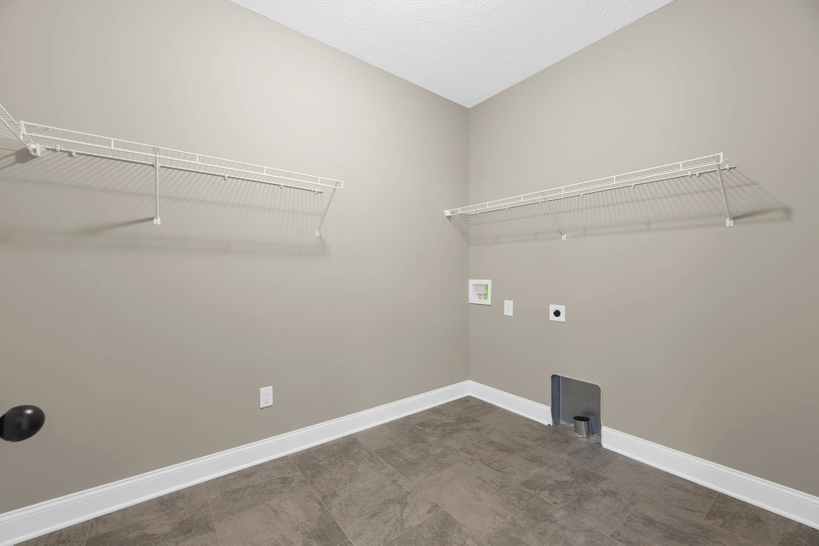 White built-in shelves against a plaster wall, gray tile flooring with white baseboards, ceiling fan overhead, metal can placed on the floor.