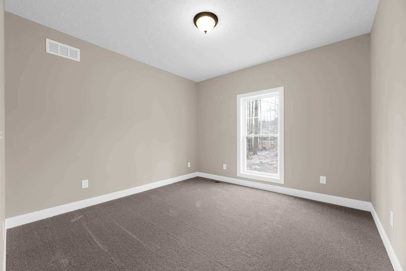 Carpeted room with white walls, large window overlooking trees, ceiling vent, and flush-mounted light fixture