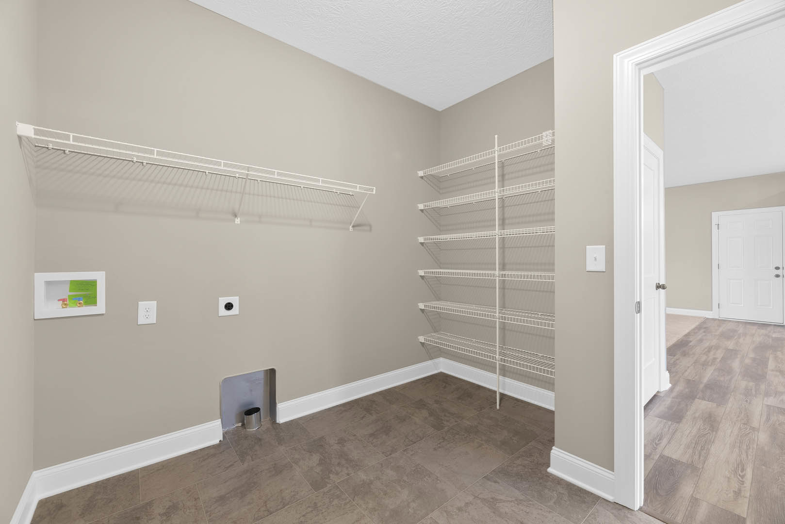 Empty closet with white wire shelving, white door with silver handles, light-colored walls and flooring