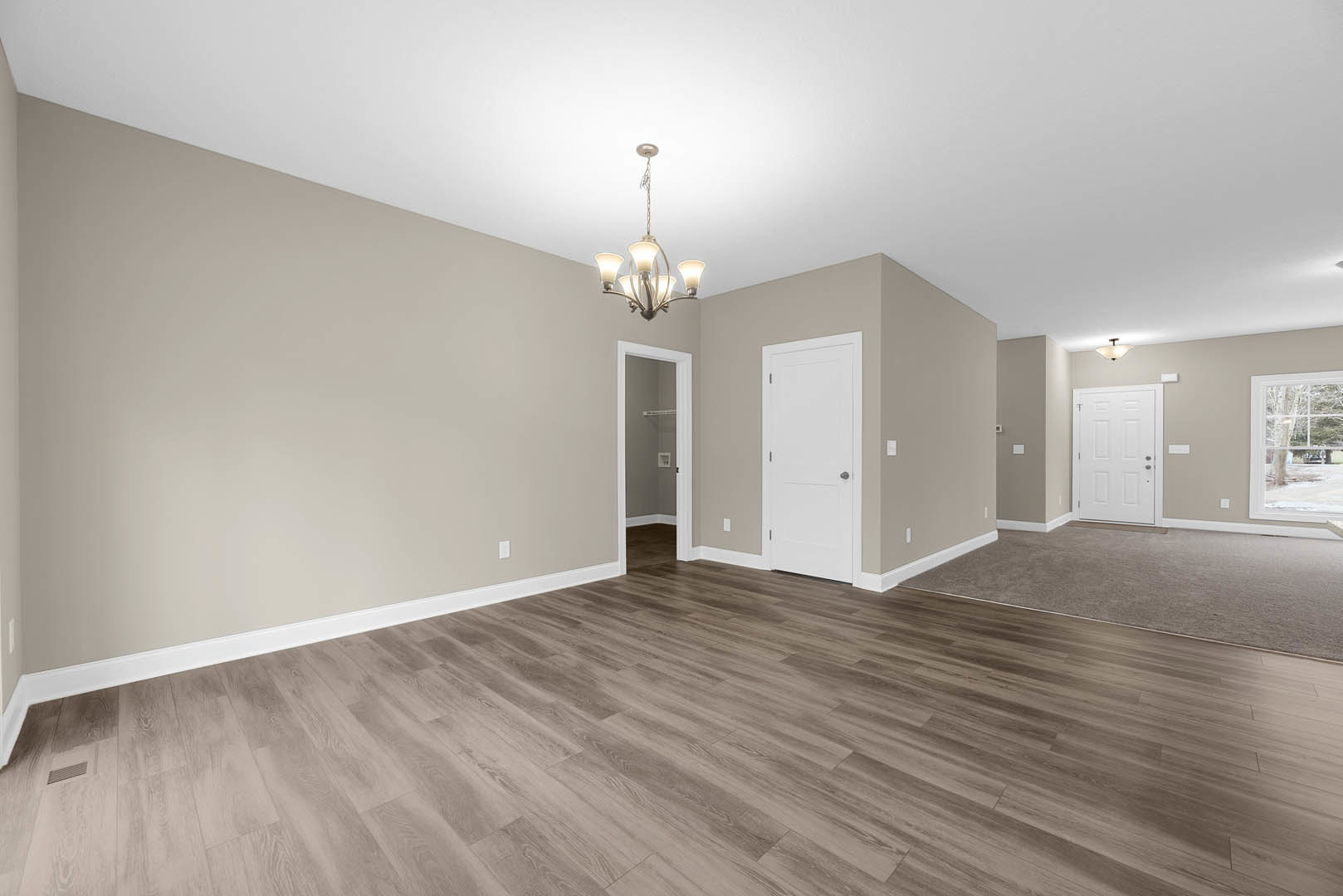 Wood floor room with white walls, modern chandelier, white door featuring silver handle and glass panel