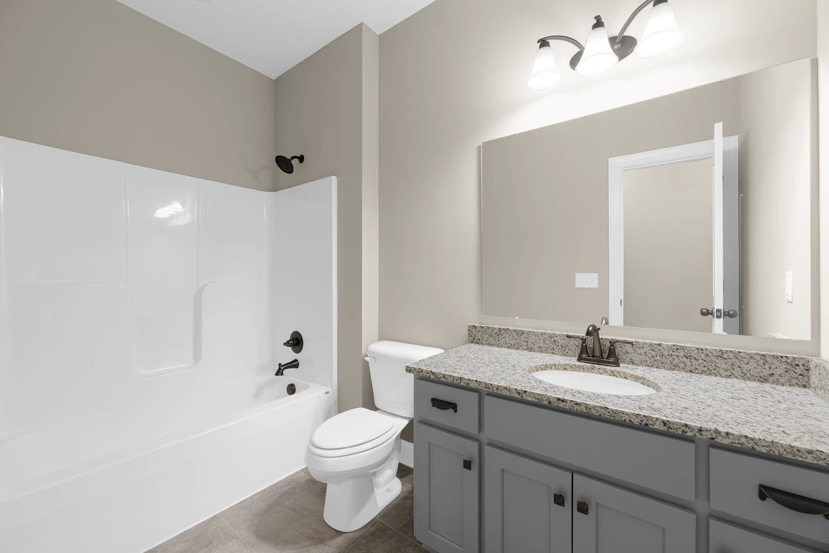 White bathroom with ceramic tile floor, wall-mounted sink, chrome faucet, frameless mirror, white toilet, and recessed lighting