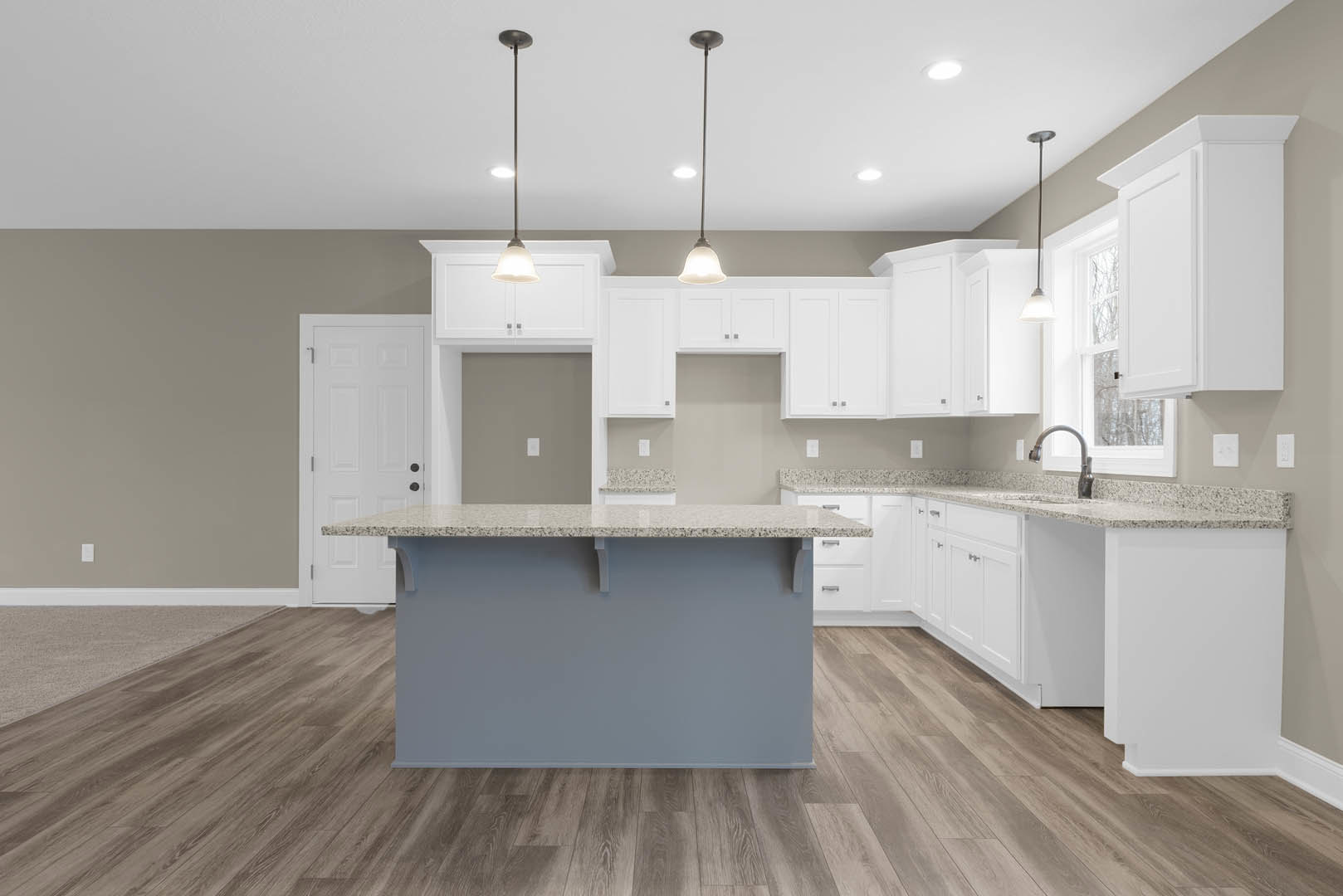 White kitchen cabinets and gray island with quartz countertop, wood flooring, black hardware on doors, pendant light fixture, open shelving, stainless steel sink.
