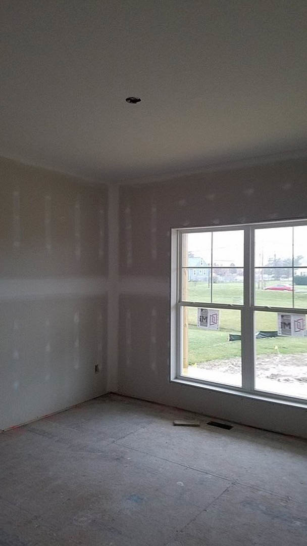 Bright room with plaster walls, large window overlooking grassy yard, concrete floor, and white ceiling