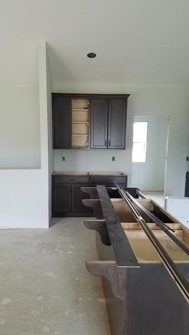 Kitchen with matte dark cabinetry, light stone countertops, stainless steel sink, metal utensil holder, plaster walls, wood dining table, large window, and neutral tile flooring
