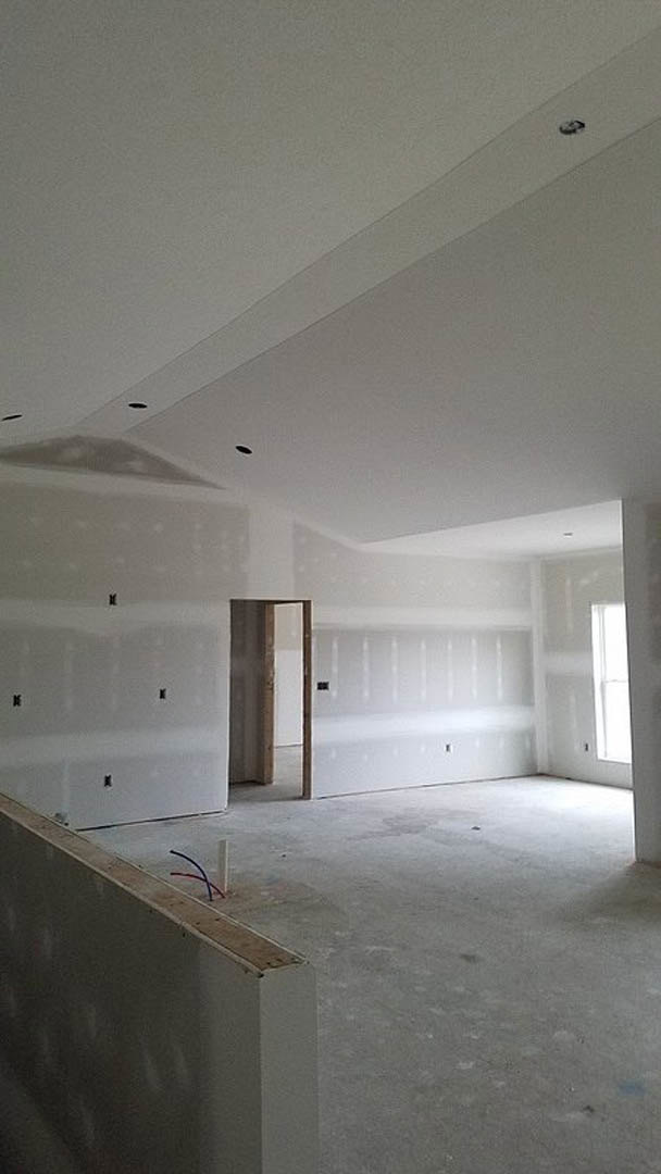 White-walled room with a wooden door, smooth plaster ceiling, and light-colored flooring