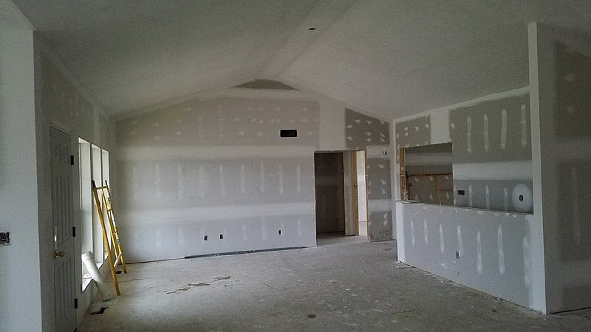 Open-concept room featuring a modern kitchen with white painted walls, a bar area, light-colored flooring, and visible ceiling fixtures.