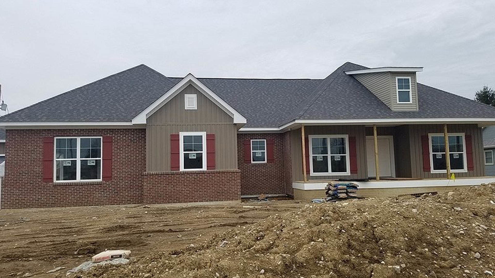 Partially built house with exposed dirt yard, white siding, sash window with white frame, and white vent featuring black lines