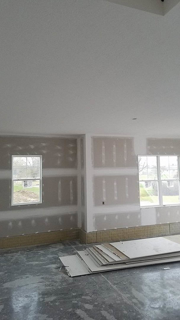 Bright room with smooth white plaster walls, large windows, light wood flooring, and minimal furnishings