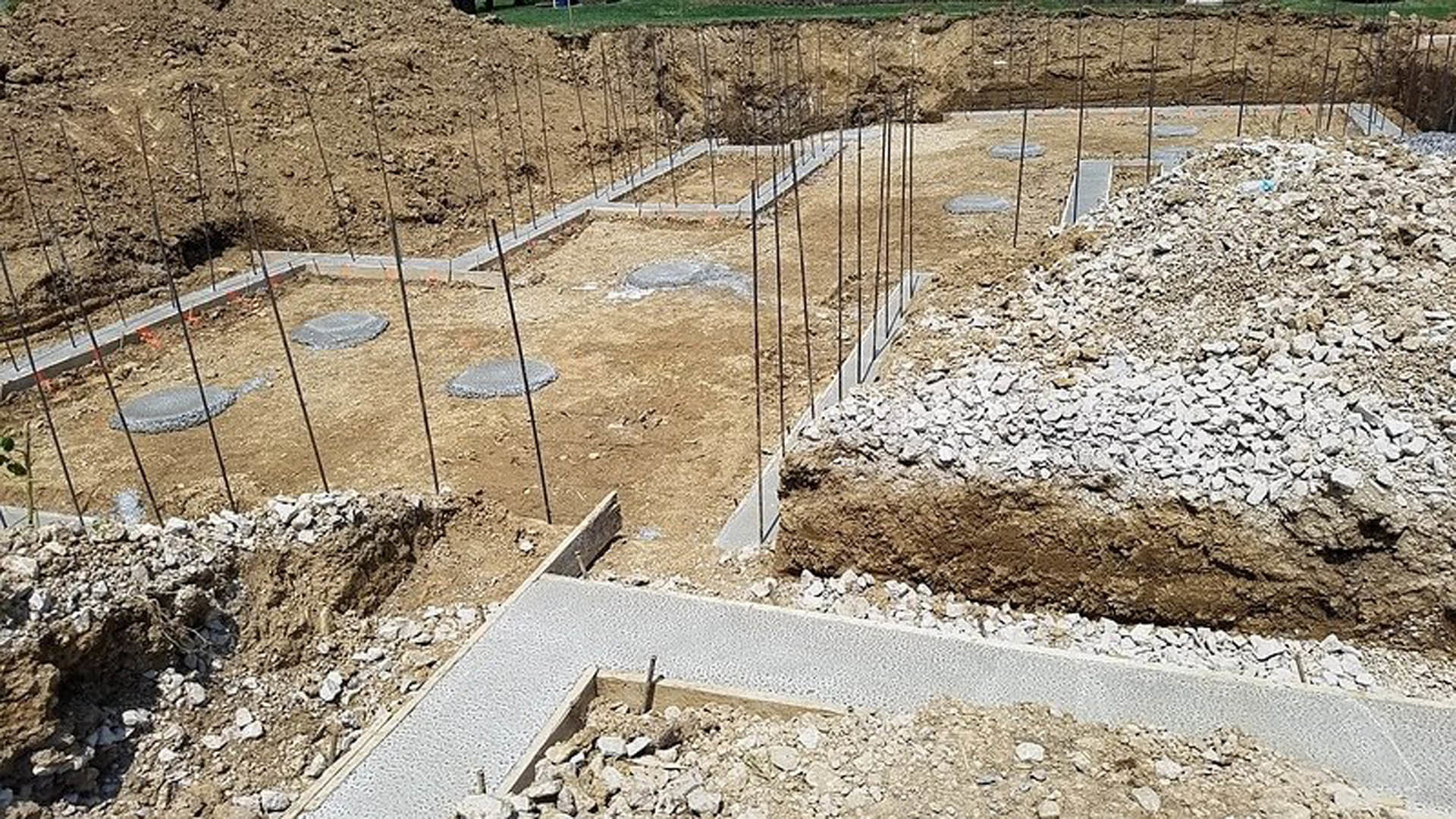 Concrete foundation slab surrounded by piles of rocks and dirt on a construction site