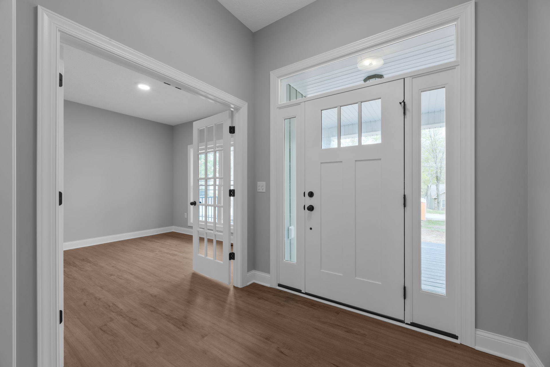 White door with glass panes set in a room featuring wood laminate flooring and plaster walls