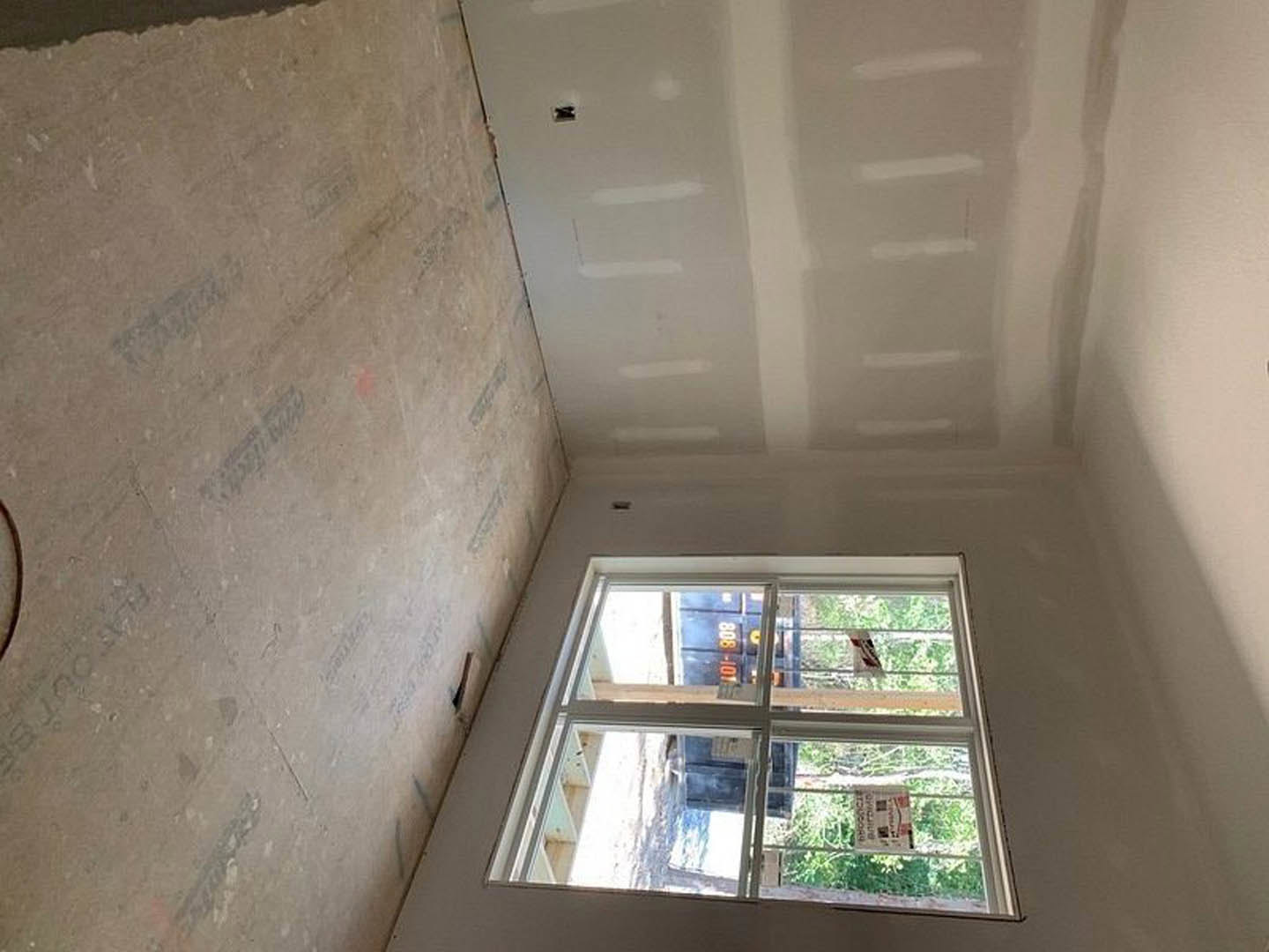 White painted wall with small holes, large window with daylight, simple interior finishes