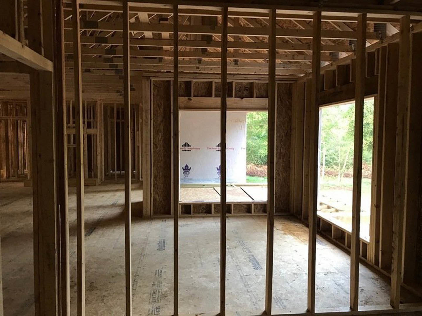 Room featuring exposed wood framing, large window with outdoor trees visible, and a screen positioned near wood beams