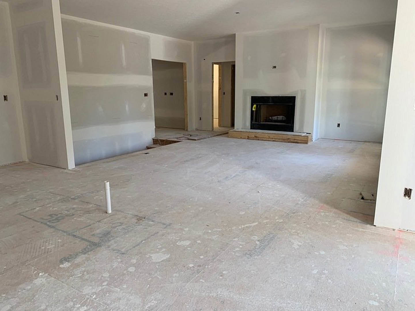Living room with plaster walls, concrete flooring, modern fireplace, large window, and visible wood trim