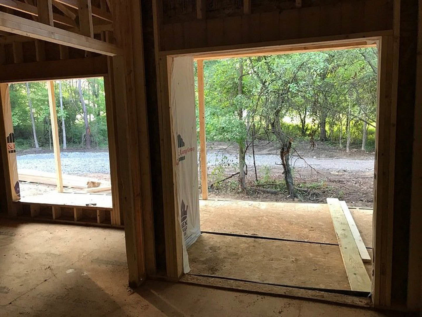 House exterior framed by a window, forest trees visible through glass, wooden window sill and trim in foreground