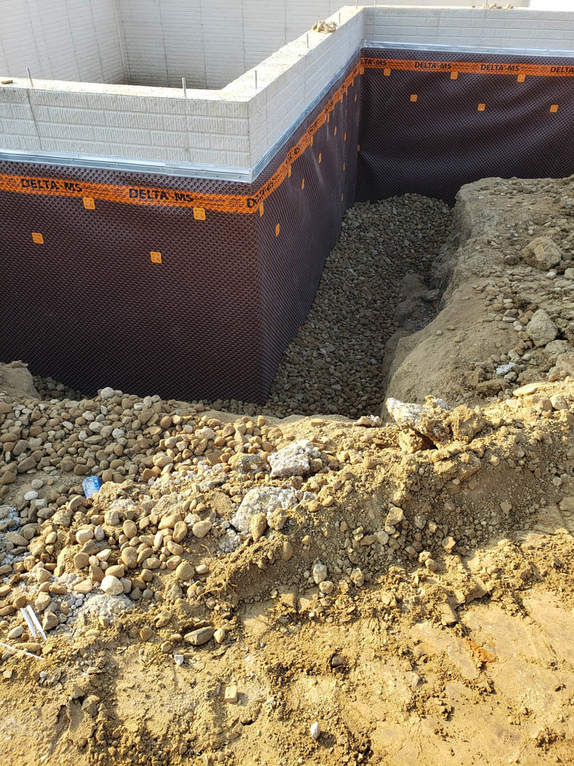 Concrete foundation slab surrounded by dirt and rocks at a residential construction site