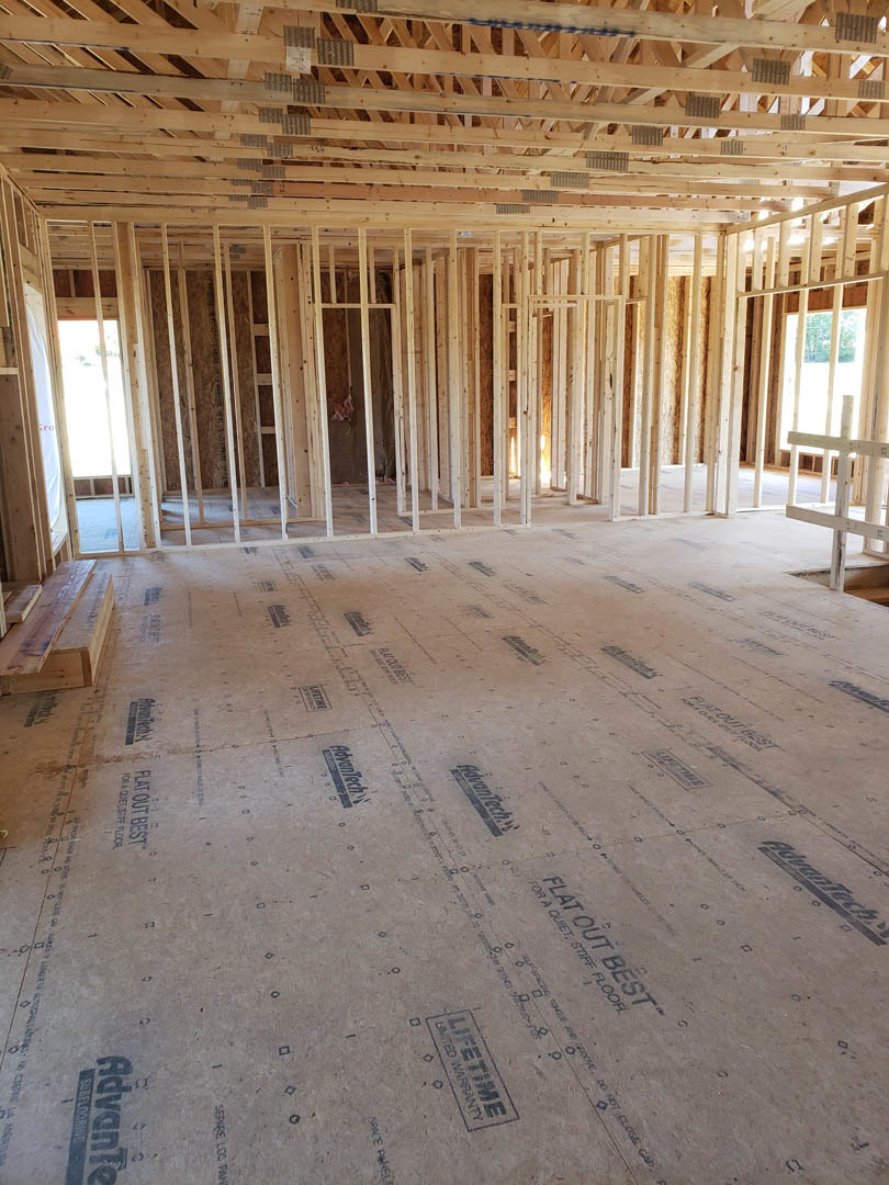 Wood-framed room under construction with exposed beams, unfinished floor marked with black text, and visible insulation; close-ups show white wooden table, wood plank, and wooden