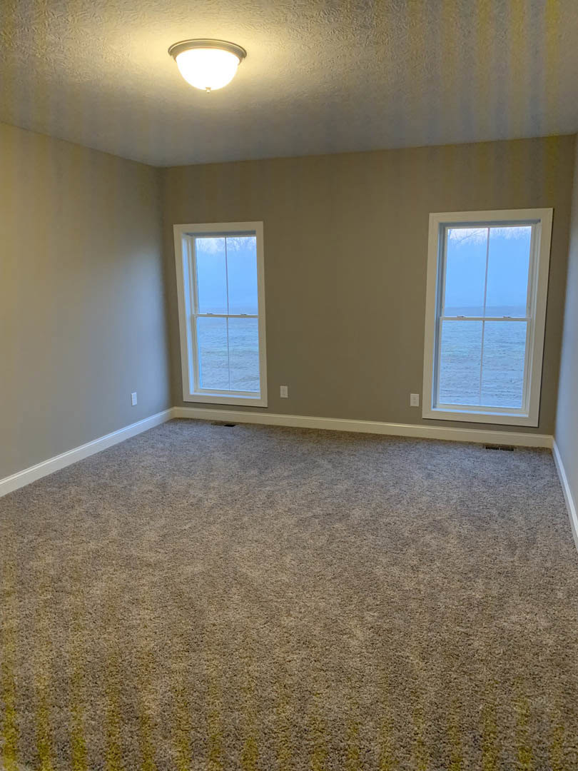 Carpeted room with two large windows, ocean view, white plaster walls, ceiling light fixture, and decorative molding