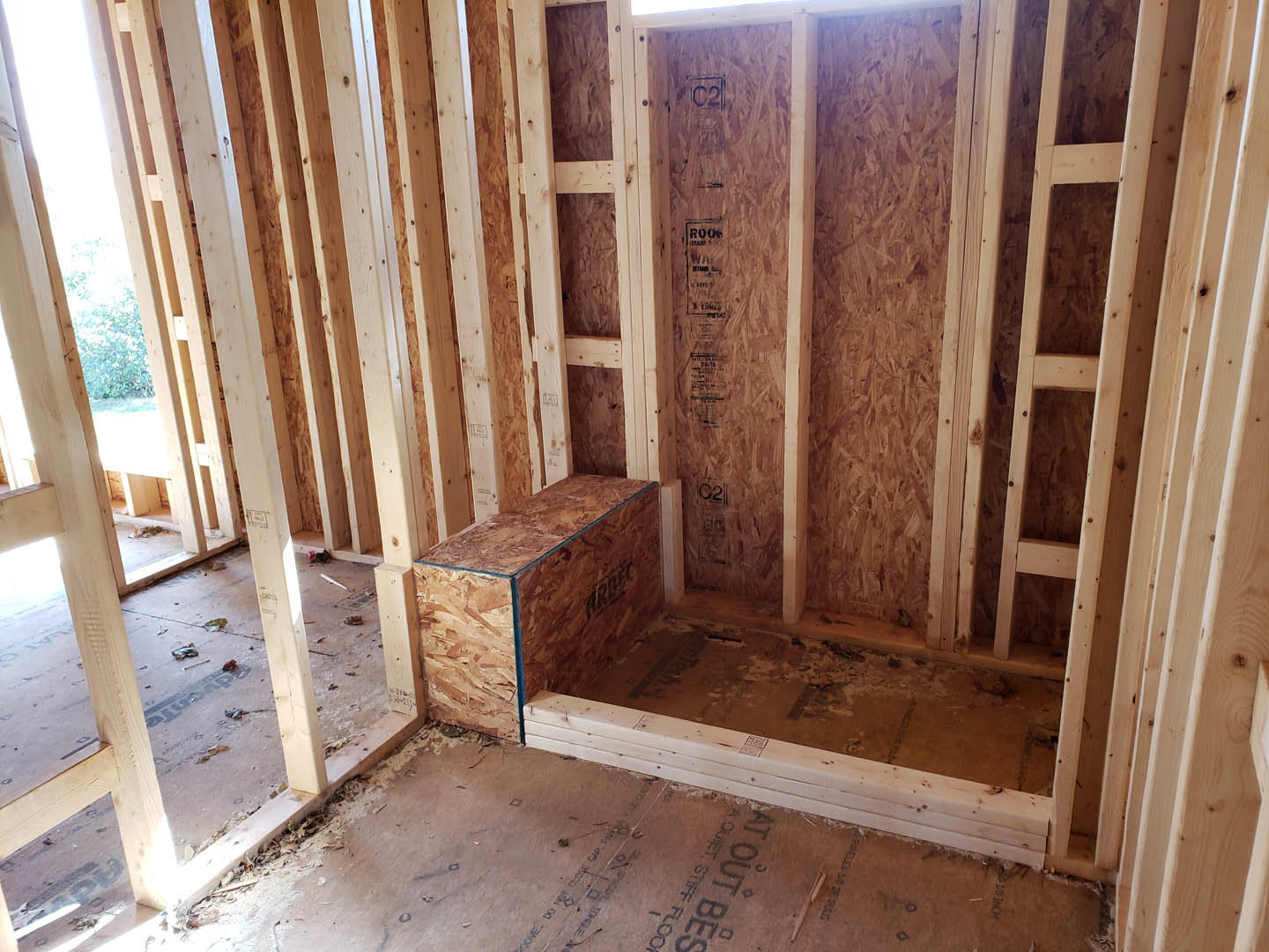 Wood-framed room under construction with exposed studs, subfloor, and a window opening