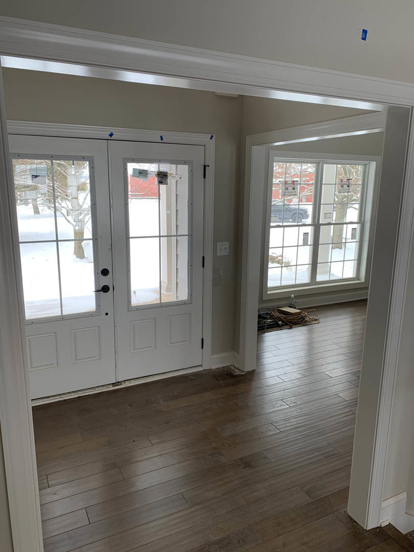 Hallway with wood flooring, white double doors, and large windows letting in natural light