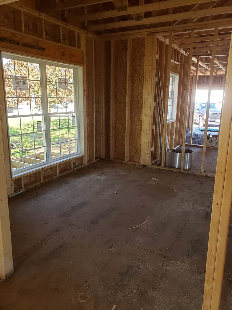 Wood-framed room with exposed ceiling beams, large window, metal ductwork, and hardwood floor